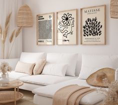 a living room filled with white furniture and pictures on the wall above it's coffee table