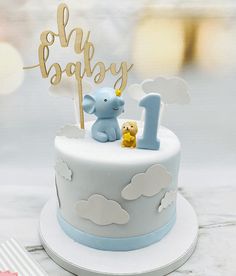 a blue and white cake with an elephant topper on it's bottom tier