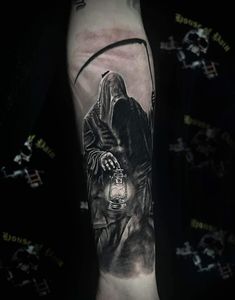 a man's arm with a black and white tattoo on it, featuring a wizard holding