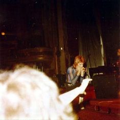 a woman sitting in front of a microphone on top of a stage