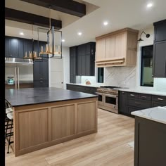 a large kitchen with wooden floors and black cabinets on the walls, along with an island