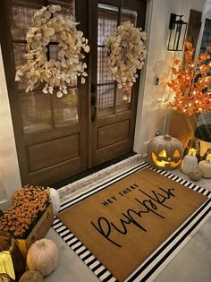 a welcome mat with pumpkins on the front porch