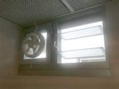 the inside of a room with two windows and a ventilator in front of it