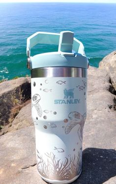 a water bottle sitting on top of a rock next to the ocean