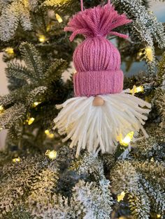 a pink and white christmas ornament hanging from a tree