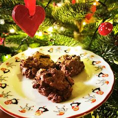 three cookies on a plate in front of a christmas tree with red hearts hanging from the branches