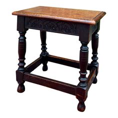 an old wooden stool with carved legs and wood seat cushion on the top, isolated against a white background