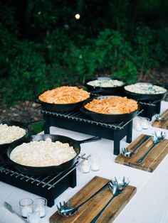 a table topped with black pans filled with food