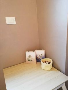 a white table with two pictures and a basket on it next to a light switch