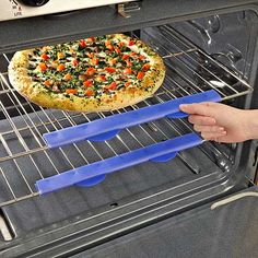 a pizza sitting on top of an oven rack next to two blue spatulas