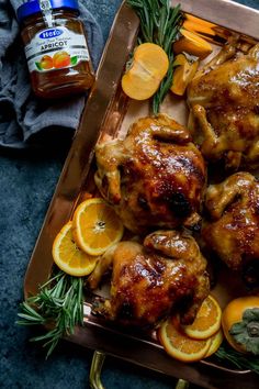 chicken with oranges and herbs on a platter next to honey, garlic, and seasoning