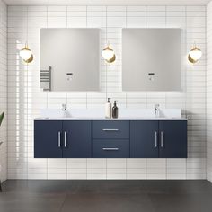 two sinks and mirrors in a bathroom with white tiles on the walls, blue cabinets