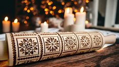 a roll of paper with decorative designs on it sitting on a table next to candles