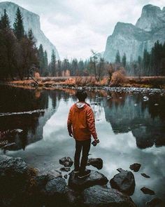 a man standing on top of a rock next to a river