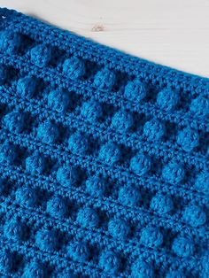 a blue crocheted blanket on top of a wooden table