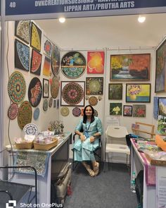 a woman sitting on a chair in front of a wall full of art