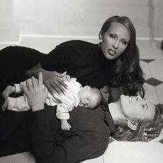 a man and woman laying on the floor holding a baby