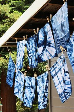 blue and white tie - dyed towels hanging on clothesline with trees in the background