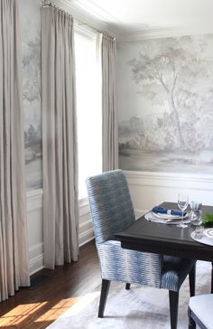 the dining room table is set with place settings for two people, and there are wallpapered trees on the walls