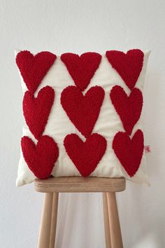 a red and white pillow with hearts on it sitting on top of a wooden stool