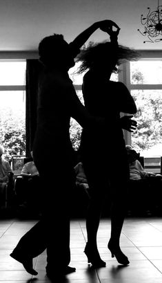 two people are dancing on the dance floor in front of a large window, one is holding her hair