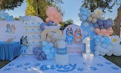 a table topped with balloons and decorations for a baby's first birthday