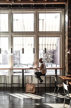 a person sitting at a table in front of large windows