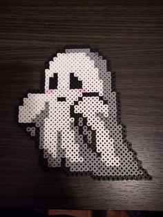 the pixel art is made out of white and black dots on a wooden surface, with an image of a ghost