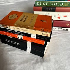 a stack of books sitting on top of a bed next to each other in front of a white sheet