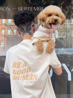 a man with a dog on his back in front of a store window that says be a good human