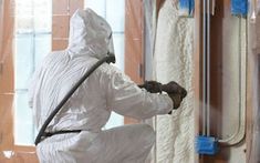 a man in white coveralls painting a wall