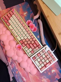 a keyboard with pink flowers on it next to a mouse pad and phone charger