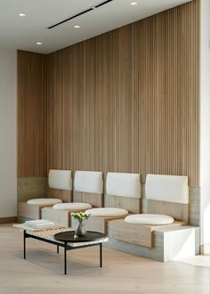 an empty waiting room with four chairs and a coffee table in front of the wall