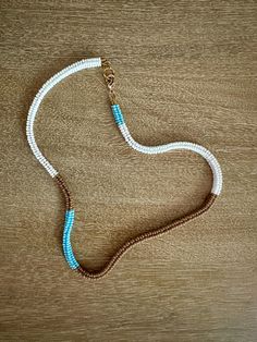 Light blue, brown, and white choker length necklace made of hand-woven glass seed beads with adjustable length closure in gold. Blue Handwoven Necklaces With Round Beads, Handmade Brown Heishi Bead Necklace, Adjustable Handwoven White Beads, Adjustable Handwoven Blue Necklace, Adjustable White Handwoven Beaded Necklaces, Handwoven Necklace, White Choker, Length Necklace, Glass Seed Beads