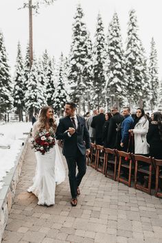 a bride and groom walking down the aisle at their winter wedding ceremony in front of an evergreen forest