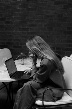 a woman sitting at a table with a laptop on her lap