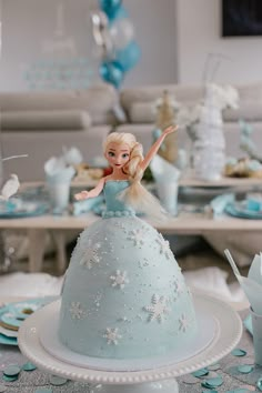 there is a cake that has a doll on the top and decorations around it in blue