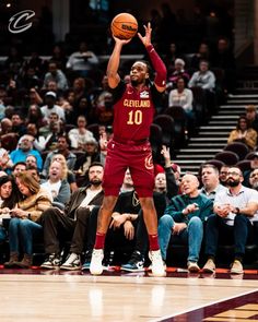 a basketball player is in mid air with the ball above his head as people watch