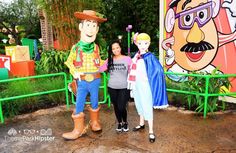 three people standing next to each other in front of cartoon characters on display at an amusement park