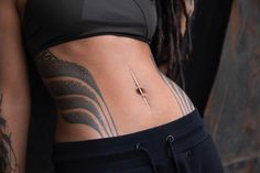 a woman with tattoos on her stomach wearing black sweatpants and a sports bra top