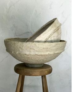 three stone bowls sitting on top of wooden stools