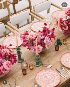 the table is set with pink flowers and candles, plates and napkins on it