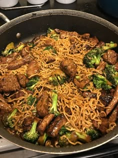 a wok filled with meat and broccoli on top of a stovetop