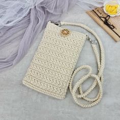 a white crocheted purse sitting on top of a bed next to a book