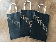 three black shopping bags with gold arrows on them sitting on a wooden floor next to each other