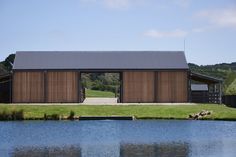 a large building sitting on top of a lush green field next to a body of water