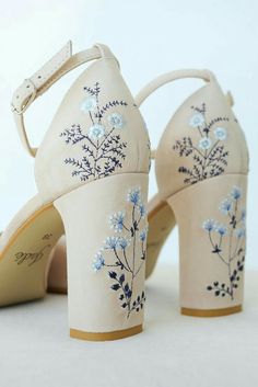 a pair of white shoes with blue flowers painted on the side and heels that are made out of canvas