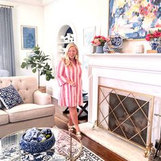 a woman standing in front of a living room fire place with blue and white decor