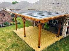 a covered patio with a table and chairs in the back yard next to a brick house