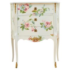 an ornate white chest with flowers painted on the drawers and gold trimming around it